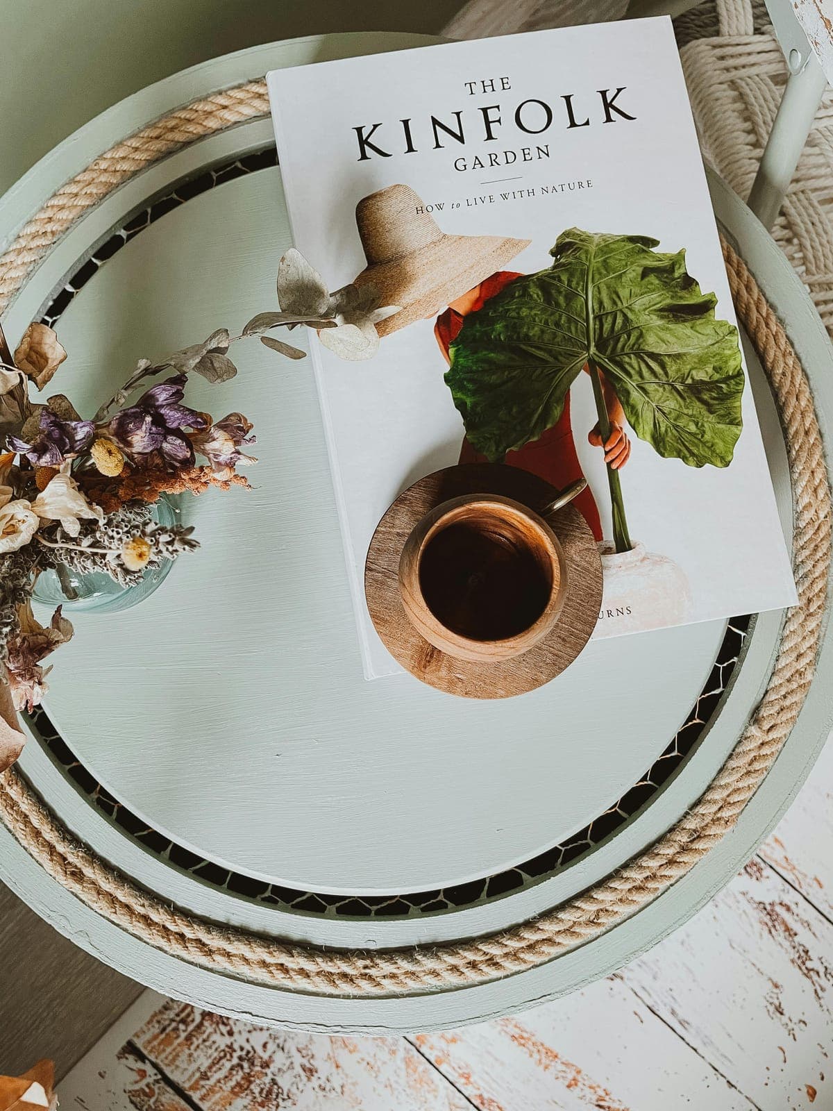 A Kinfolk book, a cup of coffee and dried flowers on a round table, seen from above