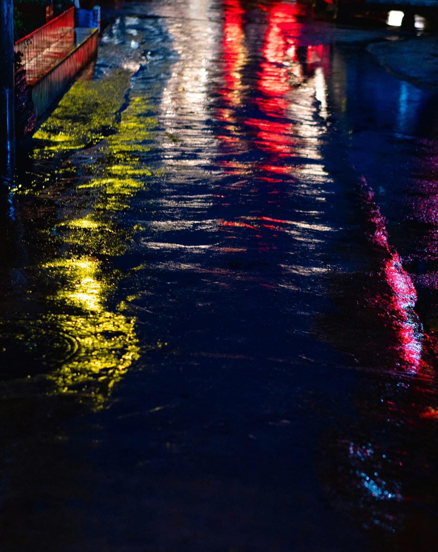 Red, yellow and blue lights reflected in a wet pavement