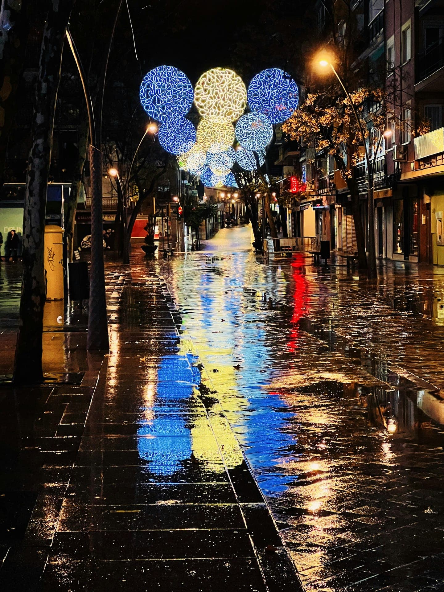 Festive lights over a wet shopping street at night