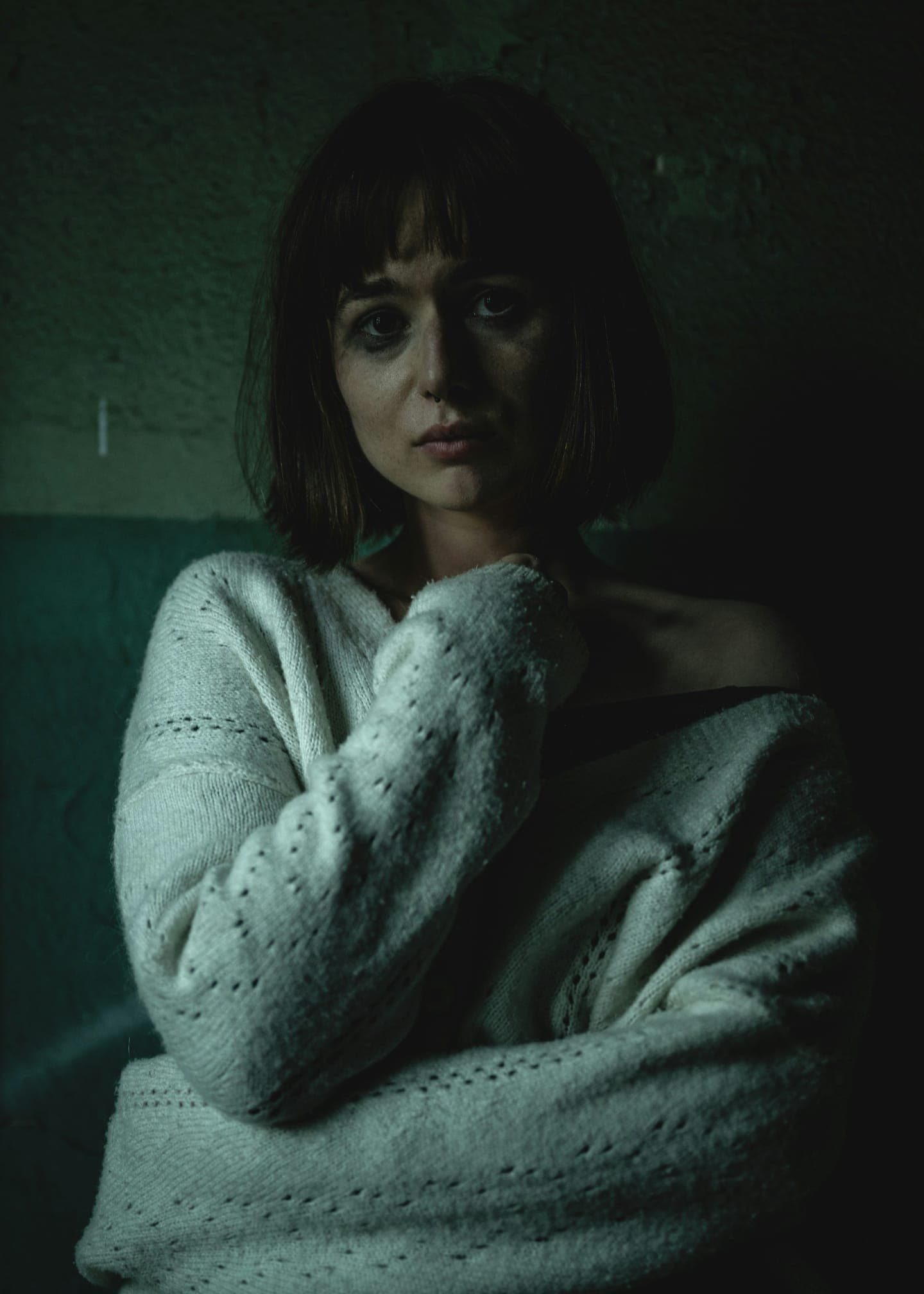 A woman with a bob and a knitted sweater in low light