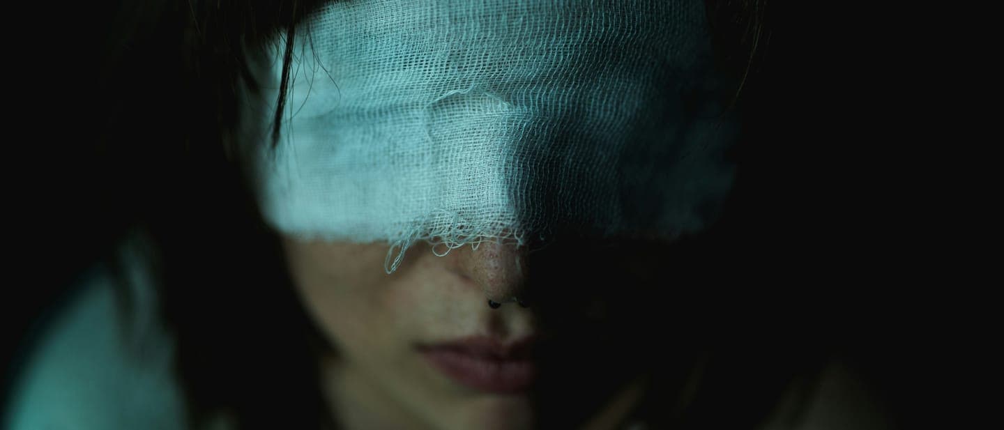 A woman's face half covered by a light cloth