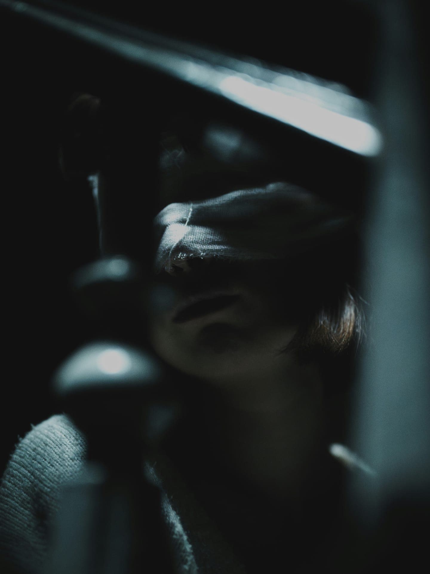 A hand raised in front of a face in deep shadow