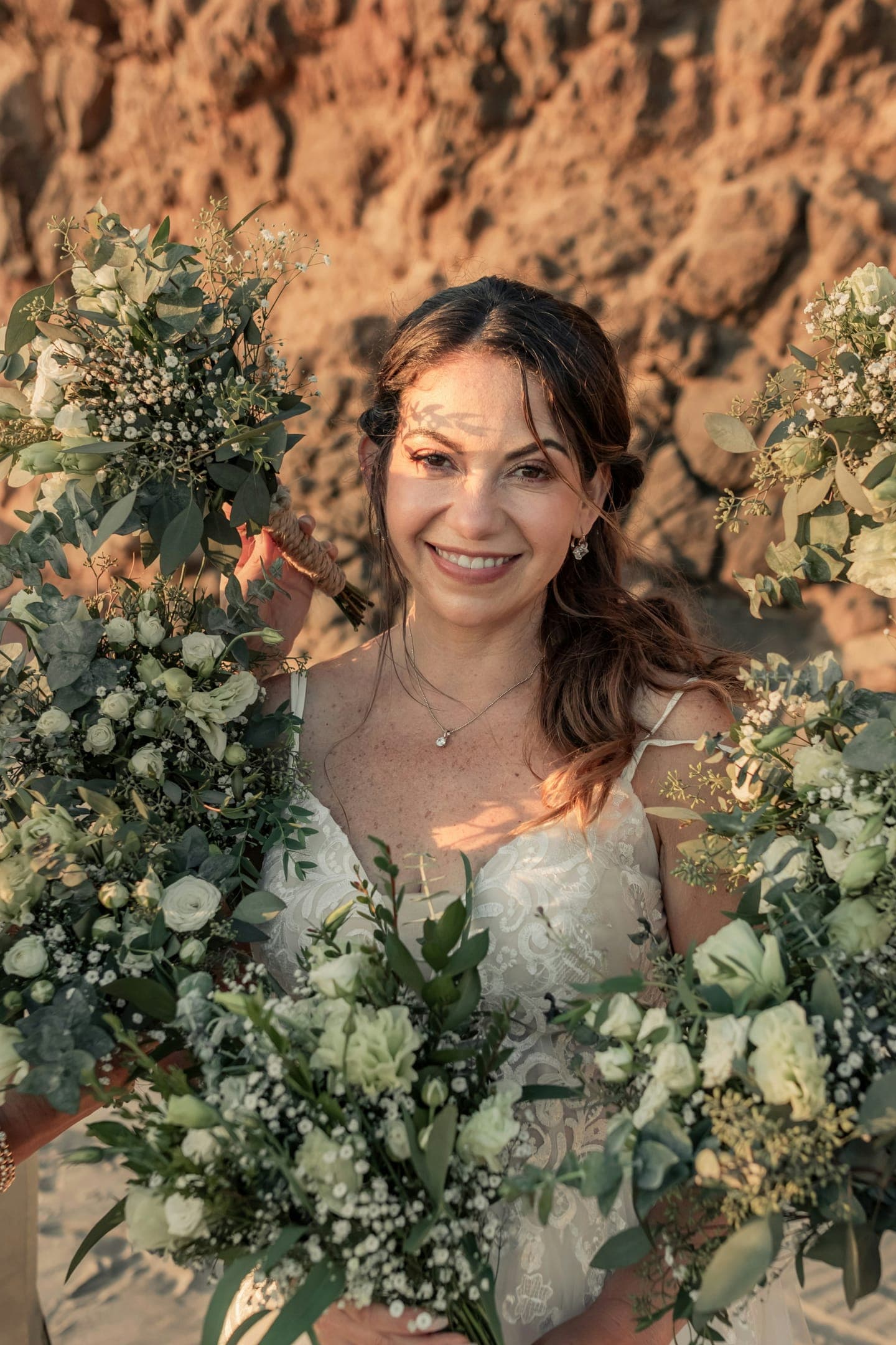 A smiling bride surrounded by white flowers and leaves