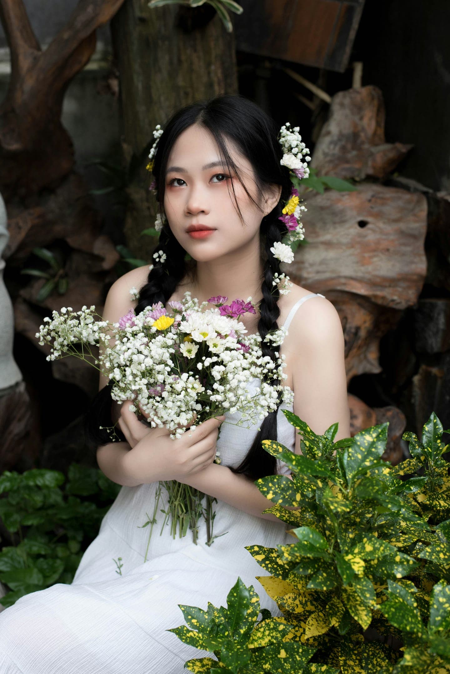 A bride with braids holding a bouquet of wildflowers among plants