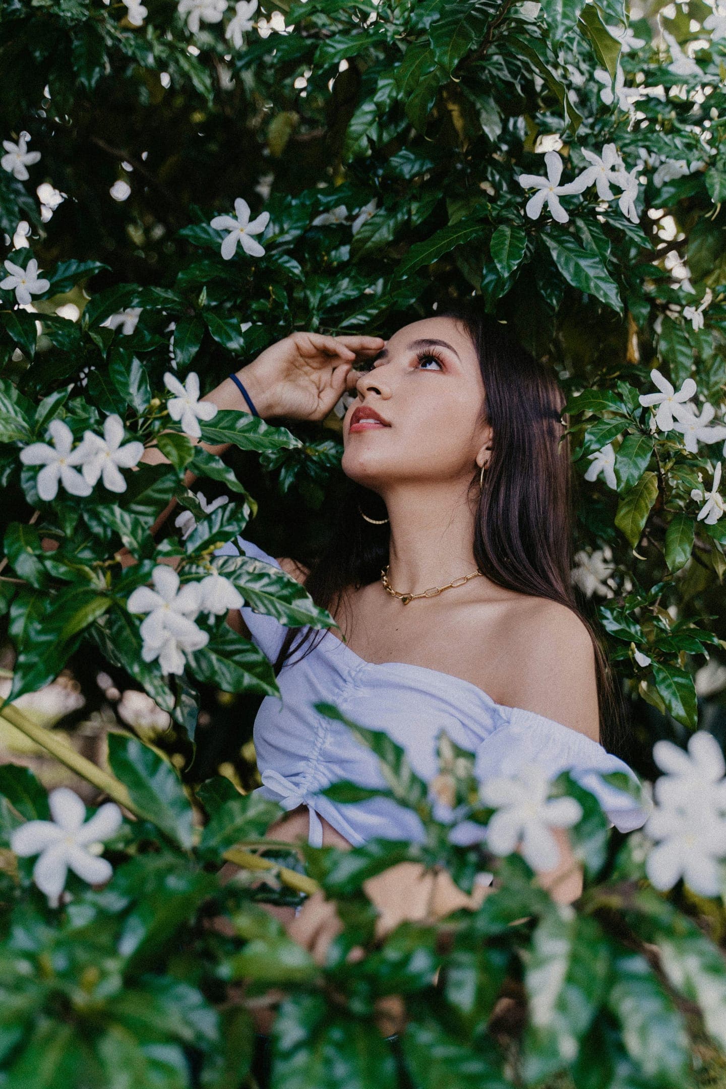 A woman with an off-shoulder top among white jasmine flowers