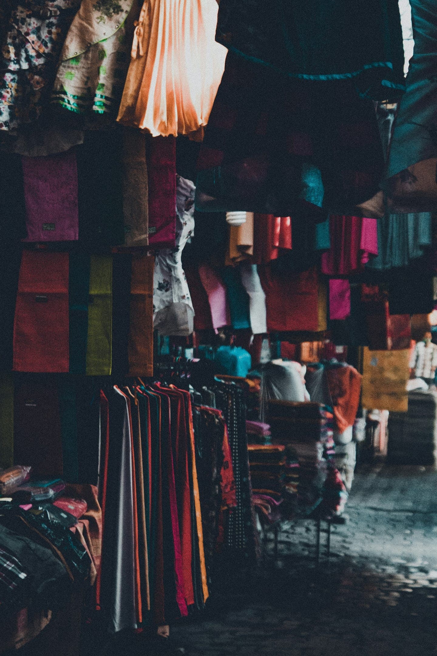 Rows of colourful fabrics hanging in a market alley
