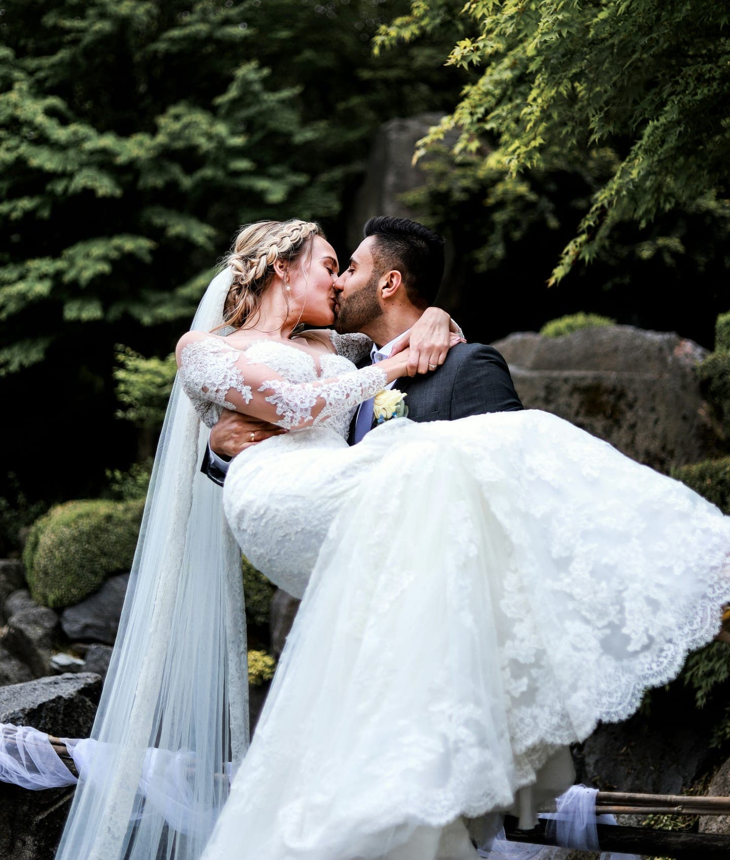 A groom lifting the bride for a kiss in a garden