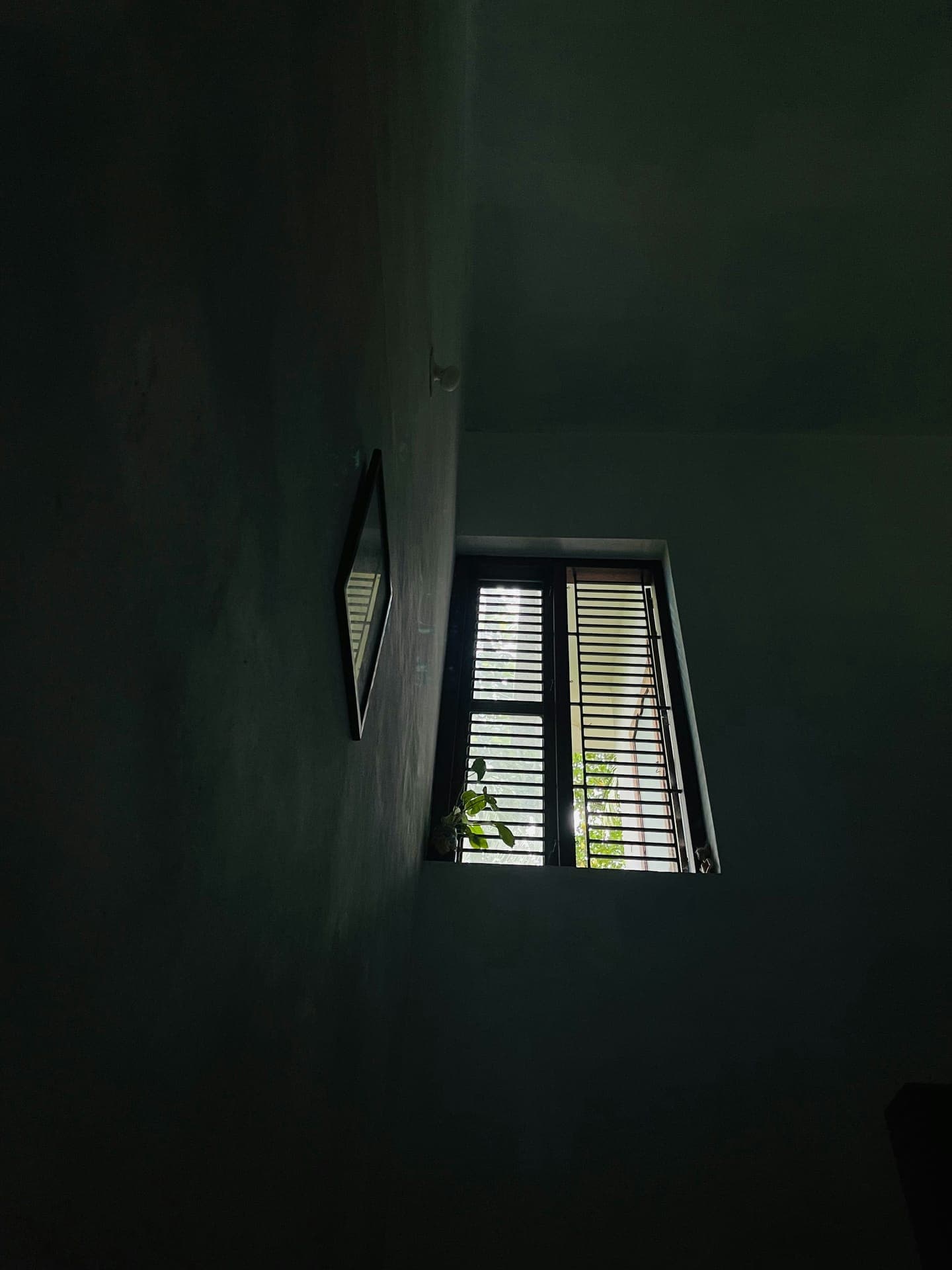 A small shuttered window high on a dark wall