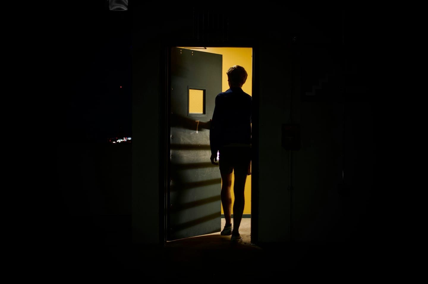 A silhouette standing in a lit doorway