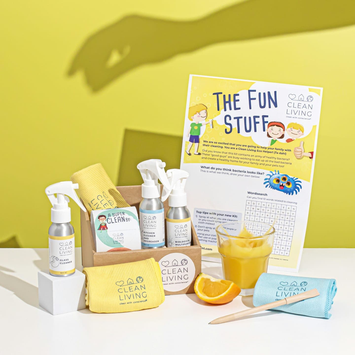 A gift box of cleaning products with orange juice on a yellow set