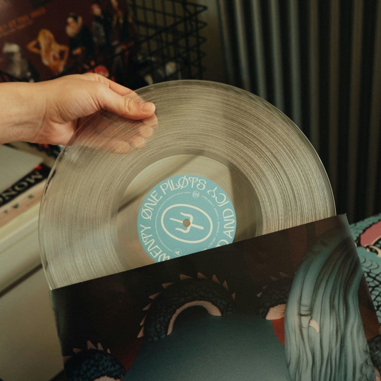 A hand sliding a clear vinyl record from its sleeve
