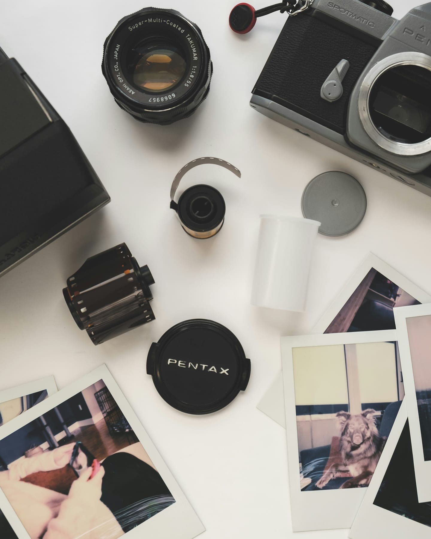 Film cameras, a lens and instant photos on a white table