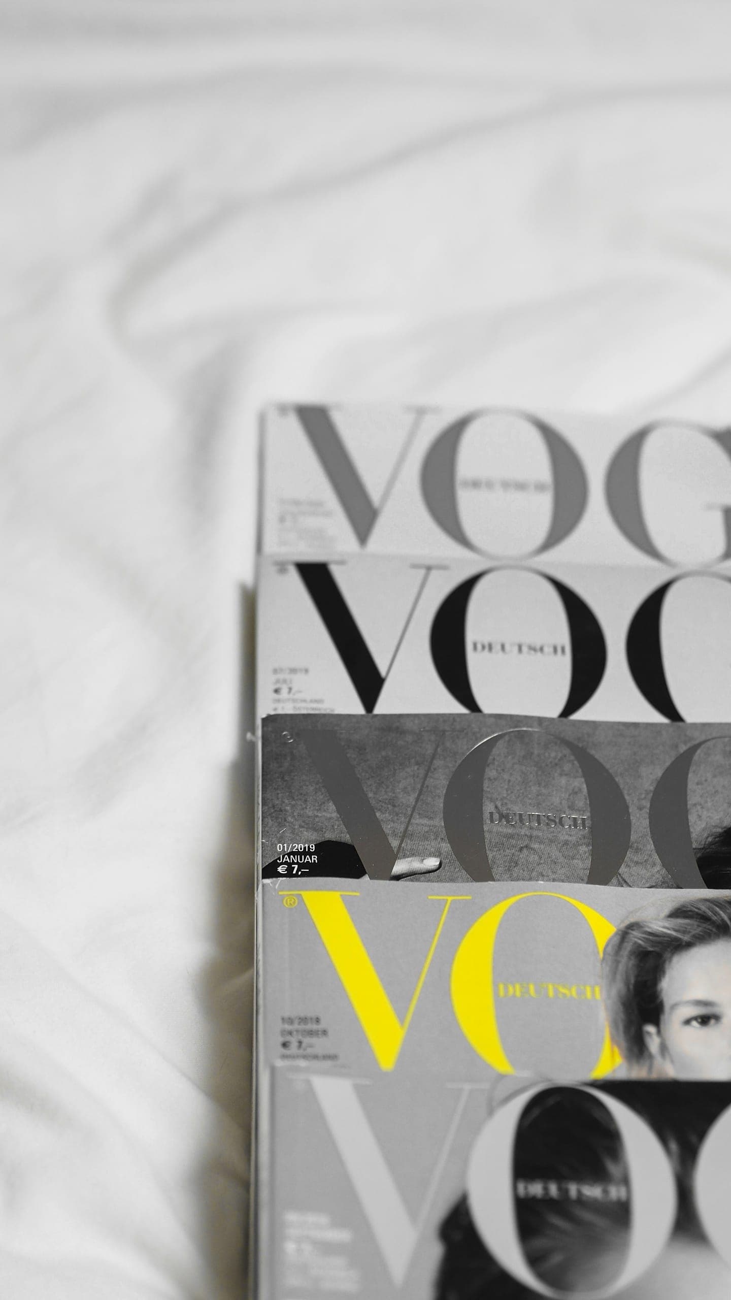 A stack of Vogue magazines on white sheets