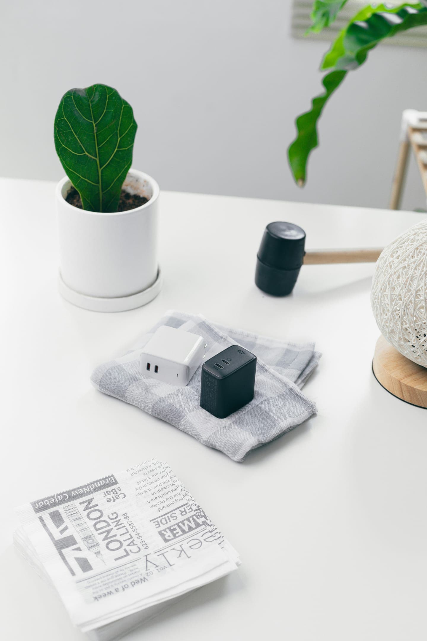 A small plant, a cloth and a newspaper on a white desk