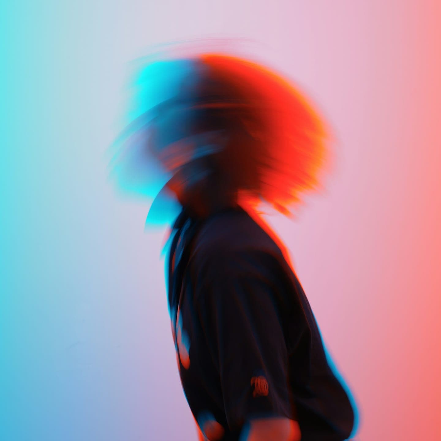 A blurred figure turning against a red and blue background