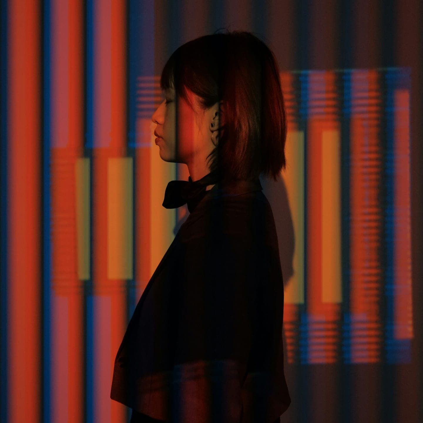 A woman in profile against coloured stripes of light