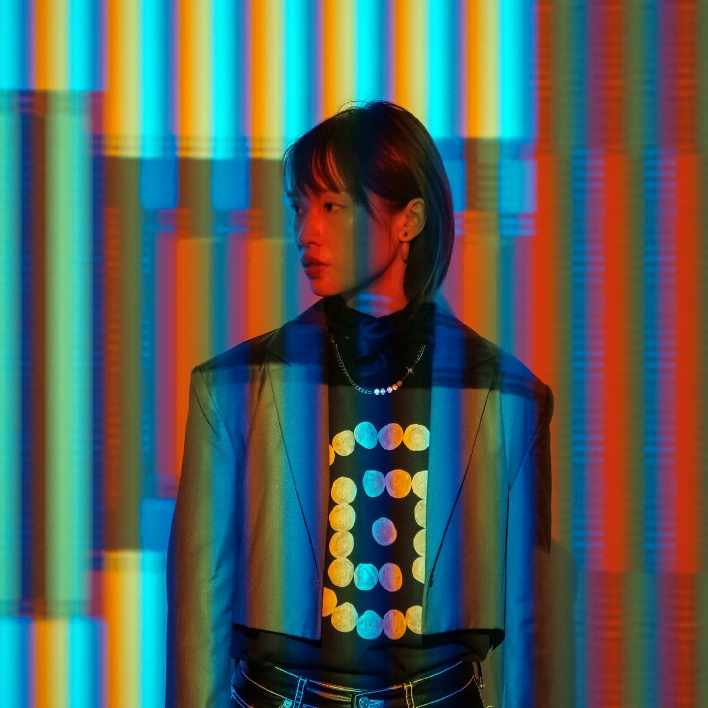 A woman in a jacket lit by stripes of coloured light