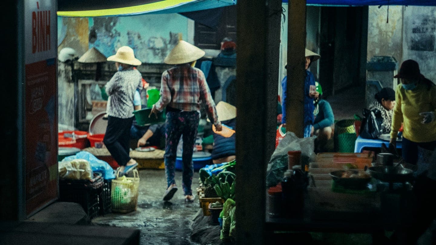 A busy street market with shoppers in conical hats