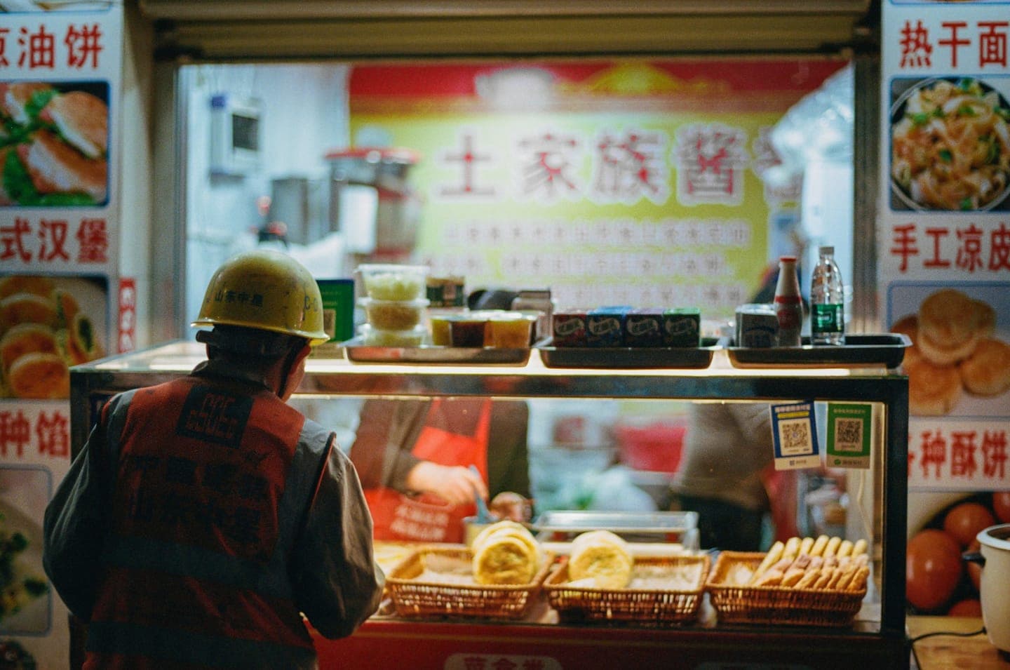 A customer at a street food counter at night
