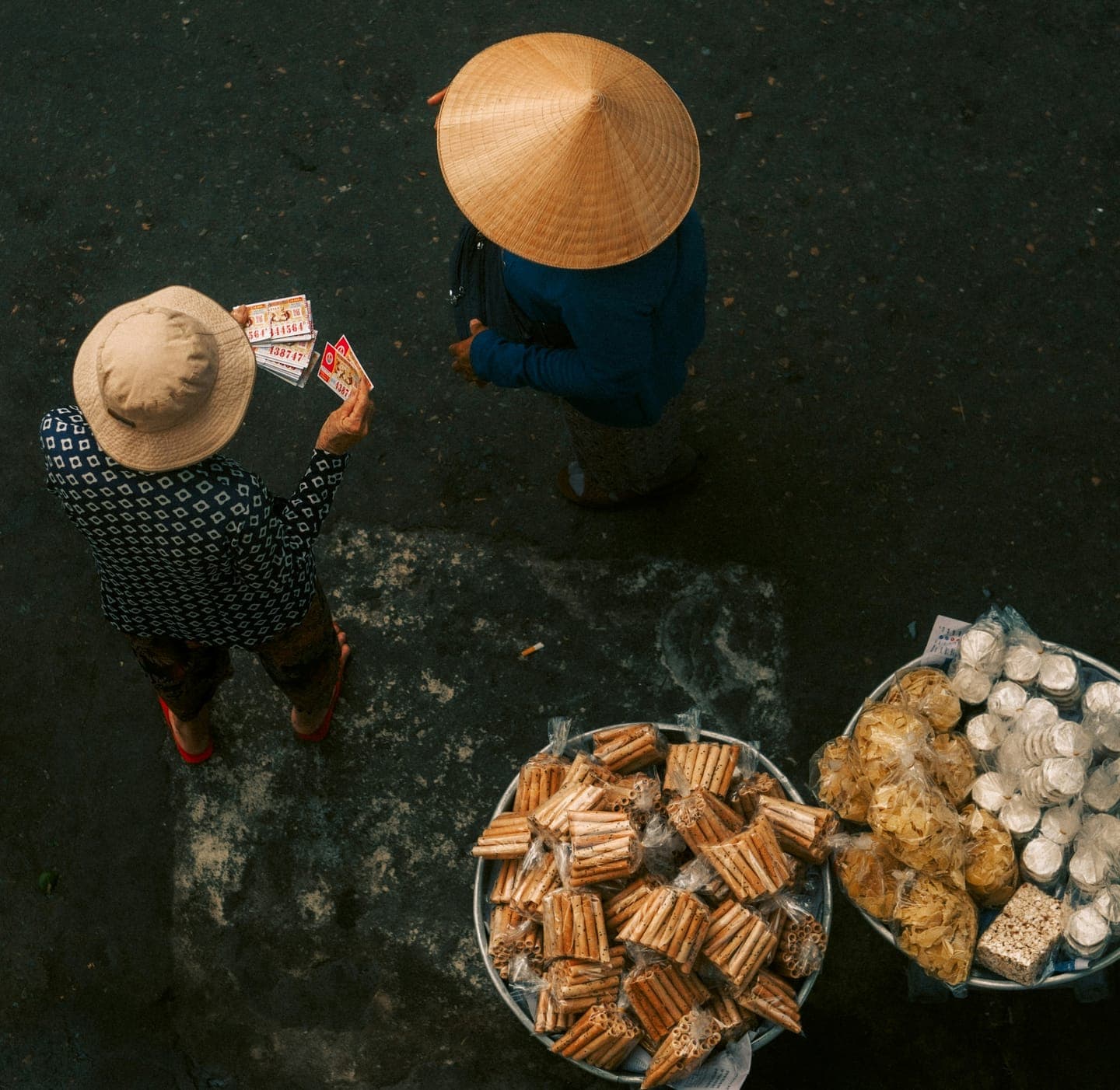 Two people in conical hats beside baskets of food, seen from above