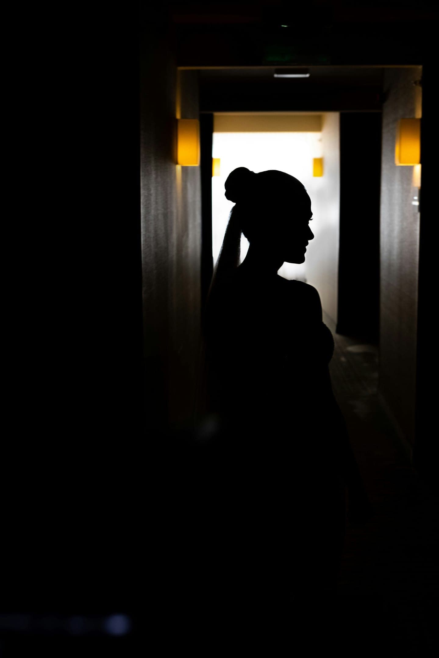 A woman's silhouette at the end of a dark hallway