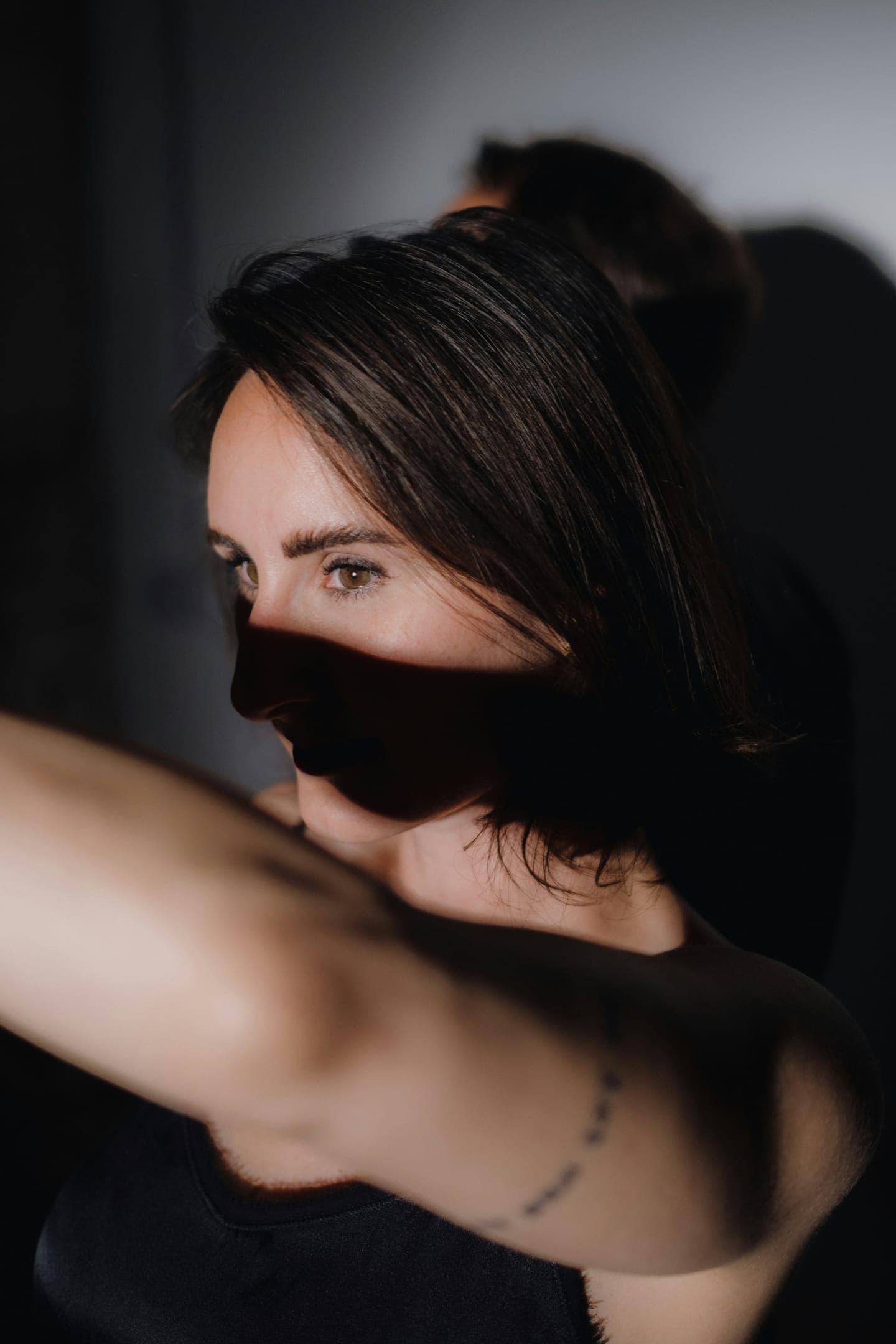 A woman covering her face with her arm in soft light