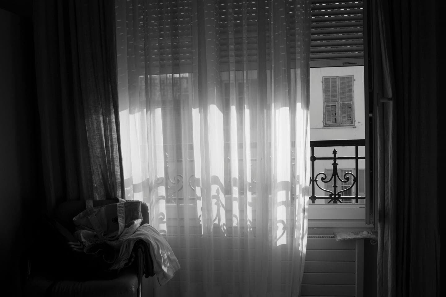 A room with sheer curtains and a balcony in black and white