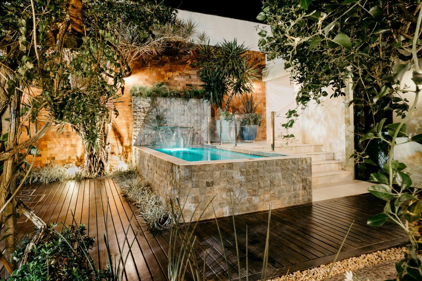 A garden courtyard with a small pool lit at night